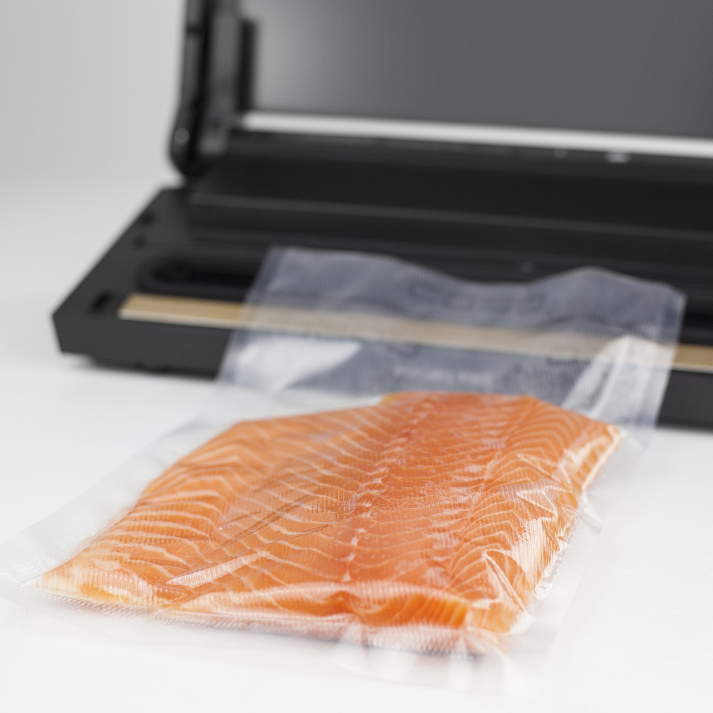 Lachsfilet in Vakuumverpackung vor Vakuumiergerät auf weißem Hintergrund