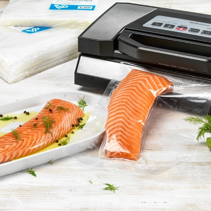 Lachsfilet in Vakuumierbeutel und auf einem Teller mit Dill und Pfeffer