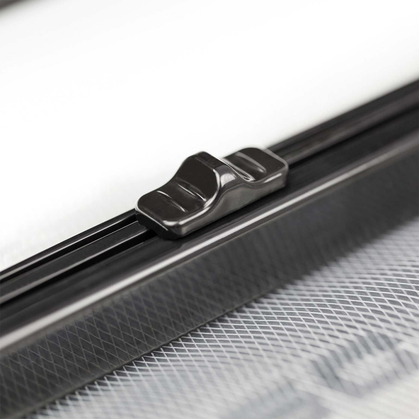 Nahaufnahme eines schwarzen Schiebereglers auf einem Fenstergitter mit weißem Hintergrund.