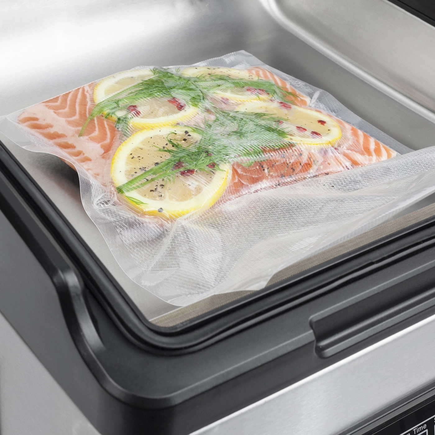 Lachsfilet mit Zitrone und Dill wird in einem Vakuumiergerät verpackt.
