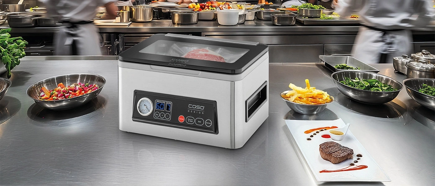 Ein Vakuumiergerät in einer professionellen Küche mit Steak und Beilagen.